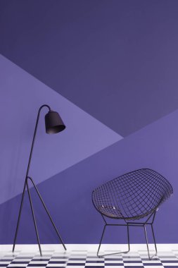Asymmetrical violet wall in modern living room interior with metal lamp and black armchair on checkered floor. Real photo clipart