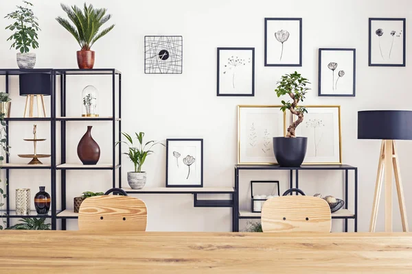 Simple gallery on a white wall in bright interior with wooden table and two chairs