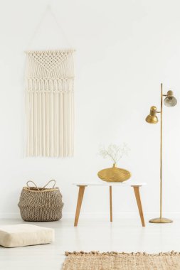 Bej DIY makrome beyaz bir duvar, ahşap mobilyalar ve altın bir boho oturma odası iç dekorasyon