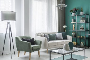 Lambanın yanındaki yeşil koltuk ve oturma odası iç dekorasyon tablo ile bej kanepe