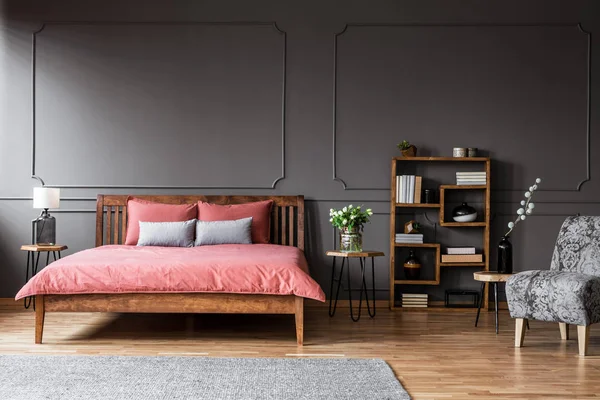 Bloemen Houten Tafel Naast Roze Bed Elegante Grijze Slaapkamer Interieur — Stockfoto