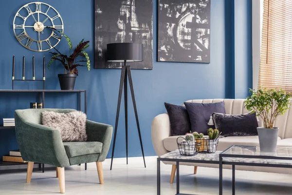 Elegant decorative cushions on a beige sofa and a modern mint green armchair in a blue living room interior