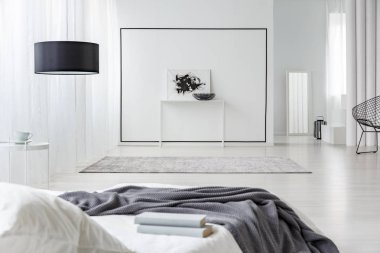 Duvardaki siyah beyaz posteri ile ferah yatak odası iç gri battaniye ile yatakta kitap