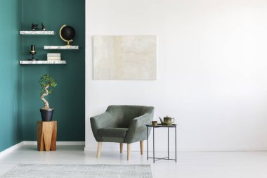 Beyaz ve yeşil koltuk, Çaydanlık Seti, ahşap bir masa ve mermer raflardan bitki ile minimalist iç