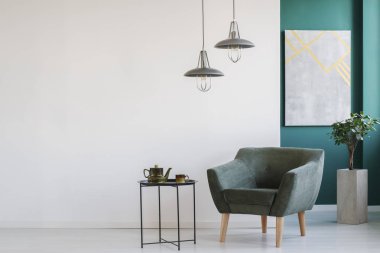 Beyaz ve yeşil koltuk ve tablo, modern lambalar, bir bitki üzerinde bir pot ve poster ayarla çaydanlık ile şık iç