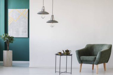 Çaydanlık modern, yeşil ve beyaz oda ayarla masa, koltuk, bitki üstünde belgili tanımlık duvar ve lambaları bir tencerede, mermer