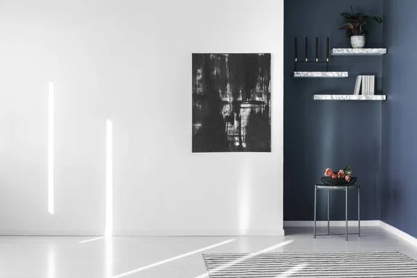 Black, abstract painting on an empty, white wall and marble shelves in a corner of a contemporary, minimalist apartment interior
