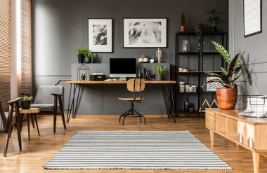 Freelancer'ın odası iç posterler ile bilgisayar monitörü ile masada ahşap sandalye