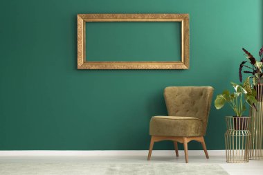 Yeşil salon iç sandalye ve taze bitkiler ile duvara asılı boş altın çerçeve