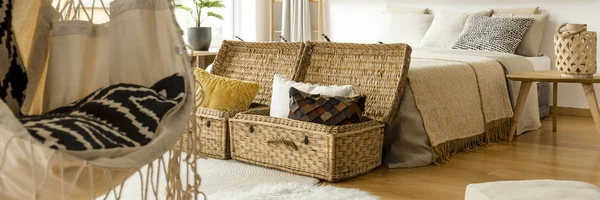 装饰枕头放在两个稻草篮 站在明亮的房间内的一张床 手工吊床椅和灯笼站在木桌上 — 图库照片