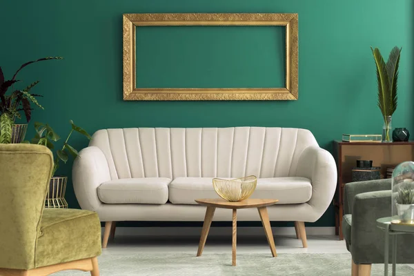 明亮的沙发站立在绿色房间内部与金碗在木桌 新鲜的植物和空的框架在墙壁上 — 图库照片