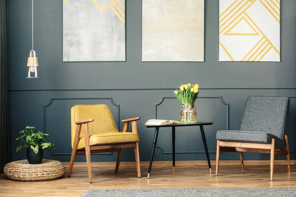 Retro chairs in vintage living room interior with paintings, lamp, plant and book on the table