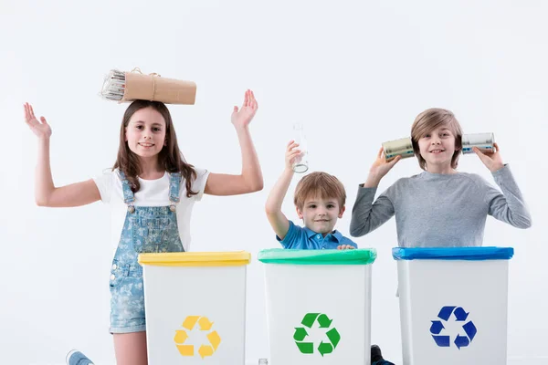 快乐的孩子们在把家庭垃圾与白色背景的回收符号隔离成垃圾桶时玩得开心 — 图库照片