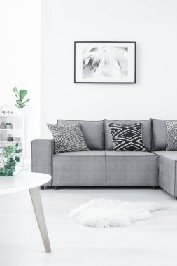 Rahat köşe kanepe desenli yastıklar, kürk halı ve beyaz duvar üzerinde hassas boyama