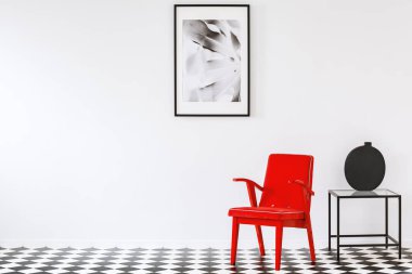 Parlak kırmızı koltukta bir sanat aşığı bir siyah ve beyaz minimalist oturma odası iç