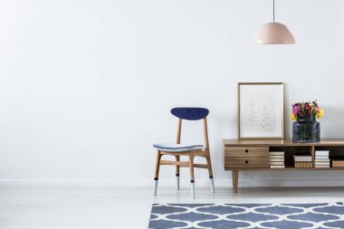 Oturma odası iç kopya alanı ile mavi bir sandalyede yanındaki posteri ile ahşap dolap çiçekler