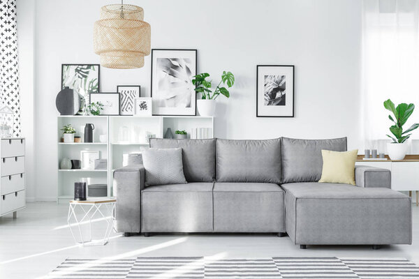 Modern studio interior with a grey corner couch, white shelves and art gallery