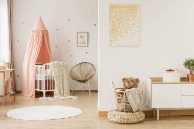 Çocuk açık alan iç gölgelikli beşiği ve kabarık bir sepet içinde oyuncak ayı ile altın poster