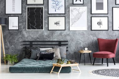 Yatak odası iç yeşil şiltenin altında Galeri posterleri ile ahşap bir masa yanında kırmızı koltuk