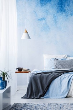 Mavi ve gri bir battaniye yatak yatak odası iç beyaz lamba ile ombre duvara var