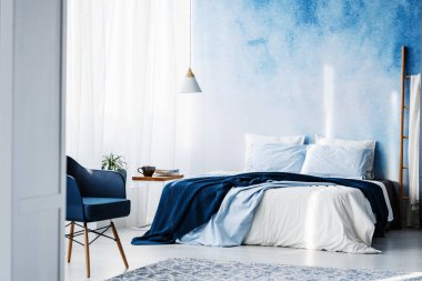 Battaniye ve yastıklar bir parlak yatak odası iç ile lacivert koltuk ve kral yatak