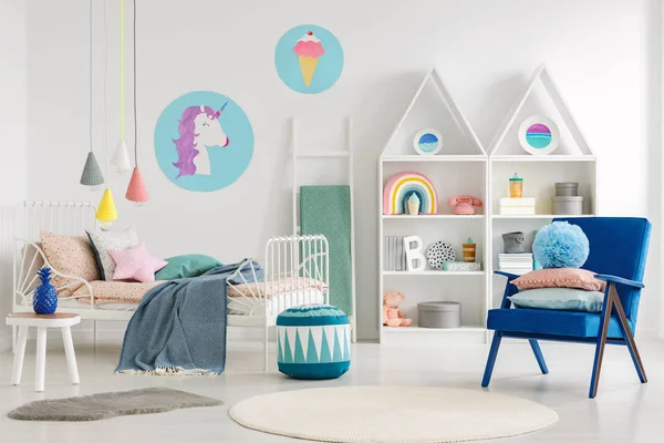 蓝色扶手椅和脚凳在五颜六色的孩子的卧室内部与独角兽海报在白色墙壁上 — 图库照片