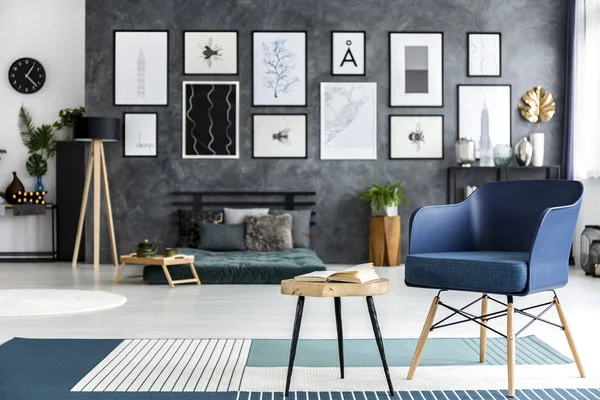 蓝色扶手椅旁边的木桌上有图案地毯在宽敞的卧室内部 — 图库照片