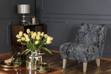 Zarif salon iç ile kalıplama ile siyah duvara koltuk desenli ve ön planda bir sehpa üzerinde sarı laleler bulanık. Gerçek fotoğraf