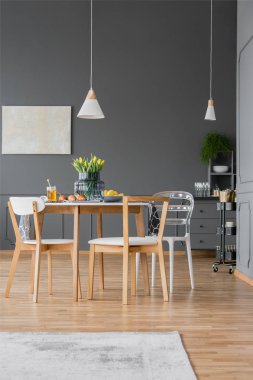 Rahat yemek odası iç gri Duvar ile sarı laleler ile ahşap masa üstünde beyaz lamba