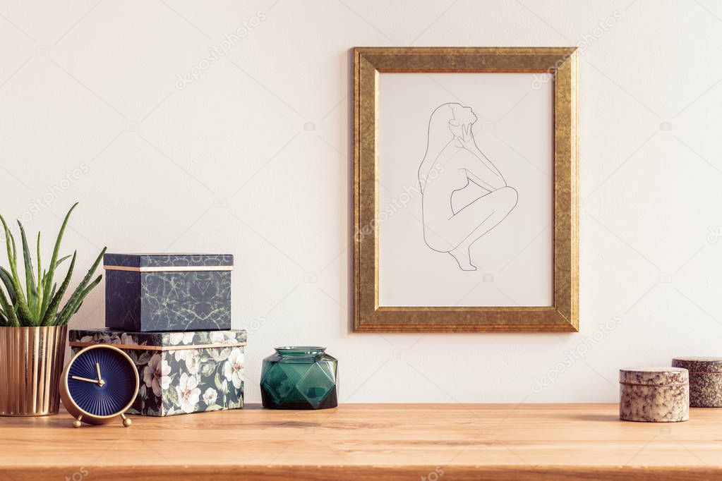 Wooden table with boxes, clock and plant as well as a painting in a golden frame on the wall