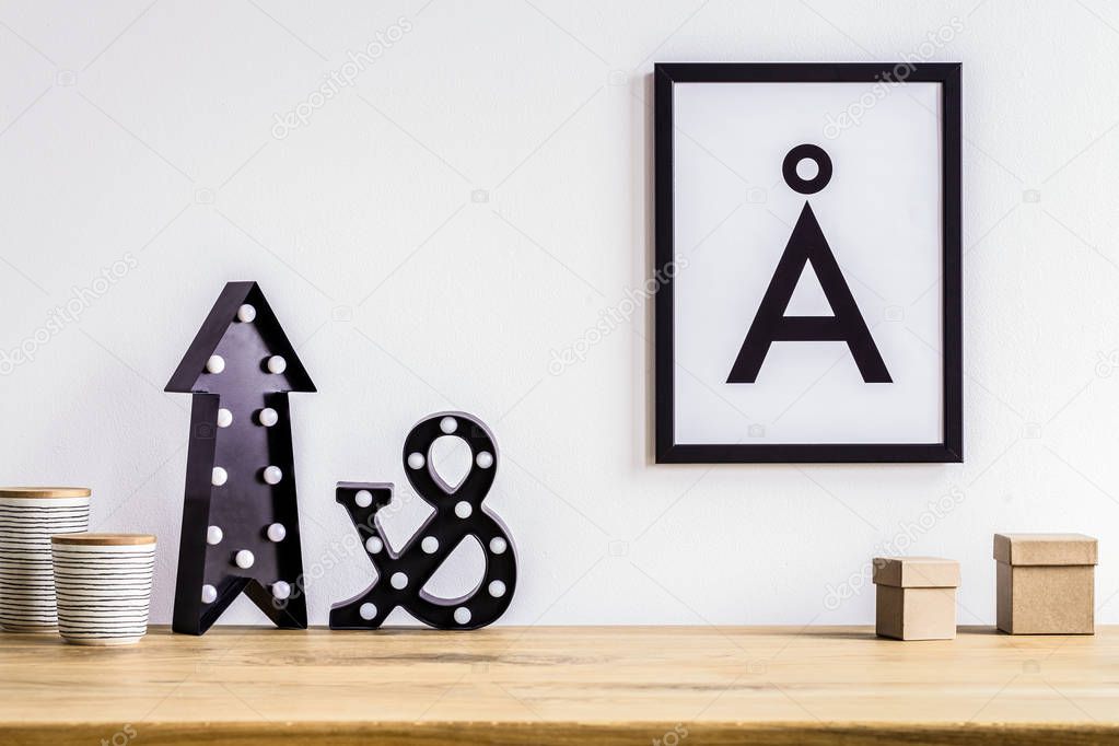 Black arrow and wooden boxes on desk against white wall with poster in simple work area interior