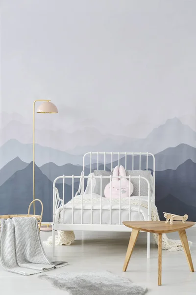 木边桌和粉粉红色地板灯由孩子的金属框架床在一个温馨和舒适的房间内部 — 图库照片