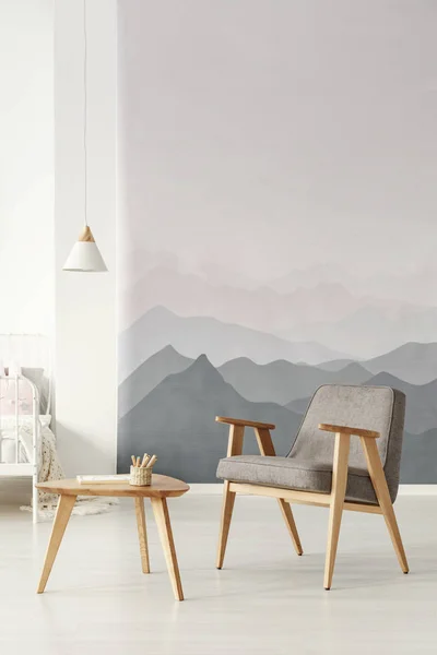 灰色扶手椅旁边的木桌在卧室内部与白色的灯和山壁纸 — 图库照片