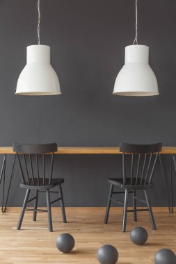 Ahşap masa yemek odası iç topları ile beyaz lambalar altında siyah sandalyeler