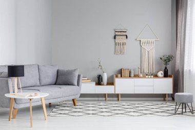 Lamba SCANDI oturma odası iç dolap yukarıda DIY dekor ile gri kanepe yanındaki masada. Gerçek fotoğraf