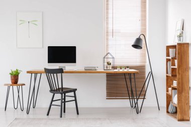 Yanındaki ev ofis iç posteri ile bilgisayar monitörü ile ahşap masa lambası. Gerçek fotoğraf