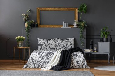 Lüks, karanlık daire odası iç rahat bir çift kişilik yatak, zarif gri mobilya, altın süslemeleri ve bitkiler