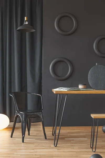 黑色椅子旁边的一个木桌对墙与圆圈在黑暗的家庭办公室内部 — 图库照片