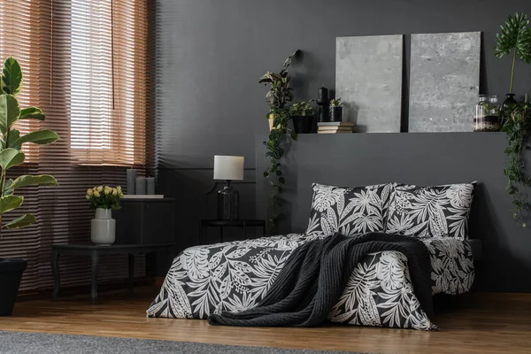 Minimalist gray paintings, elegant furniture and decorations in a dark monochromatic bedroom interior