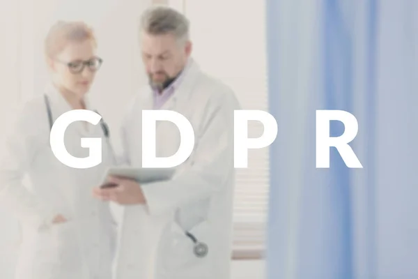 Two doctors sharing tips and information about the new legislation concerning data protection. GDPR banner on a blurred photo
