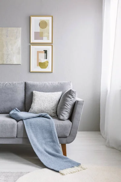蓝色毯子在灰色沙发对墙壁与金子绘画在客厅内部 真实照片 — 图库照片