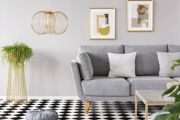 客厅的真实照片在墙上的金色海报 灰色沙发与垫子和格子地板 — 图库照片