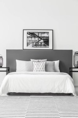 Poster üzerinde en az otel yatak odası iç desenli halı ile beyaz yatak yatak başı