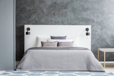 Tek renkli yatak odası iç beton duvara beyaz yatak başı yatak üzerinde gri bedsheets