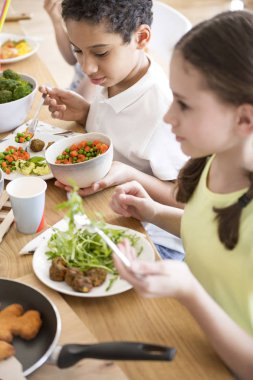High angle of children eating vegetables for dinner at school clipart