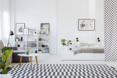 Rahat bir gri yatak beyaz bir platform ve bir kanepe yanındaki ahşap bir masa üzerinde bir açık alan daire içi gerçek fotoğraf