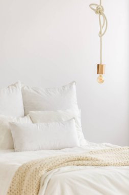 Yakın çekim yatak odası iç İskandinav tasarım bir beyaz yatak ve modern avize