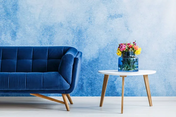 Blumen Auf Weißem Holztisch Neben Marineblauer Wildledercouch Eleganten Wohnzimmerinterieur — Stockfoto