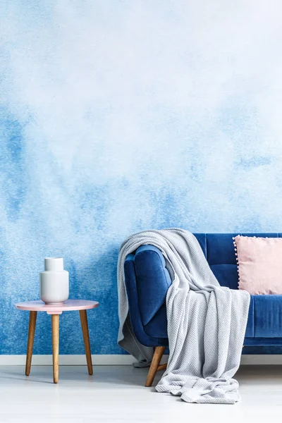 空の壁とリビング ルームのインテリアに白い花瓶とスツールの横にある灰色の毛布とソファのトリミング写真 — ストック写真