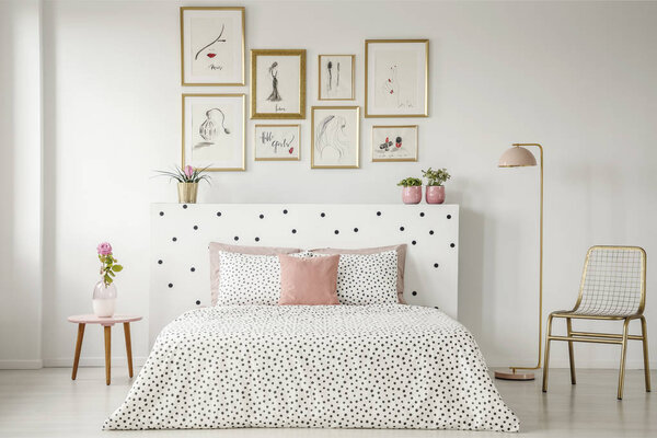 Bright bedroom interior with dotted sheets, headrest, double bed, gold accents and art gallery above